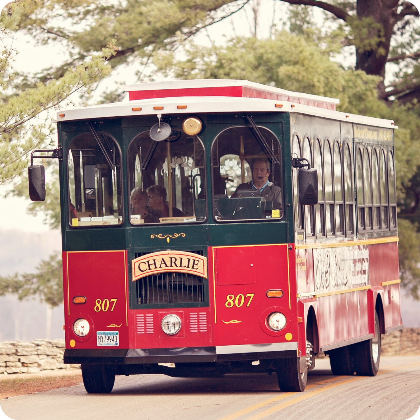 A red and green vintage trolley named Charlie taking folks on a tour around the city of Rochester MN